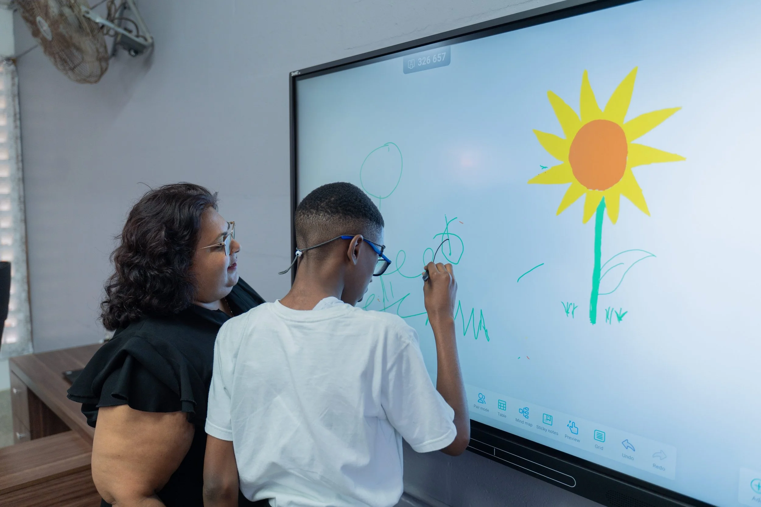 Principal of School for the Blind Roma Maraj guides this student on how to use the smartboard.