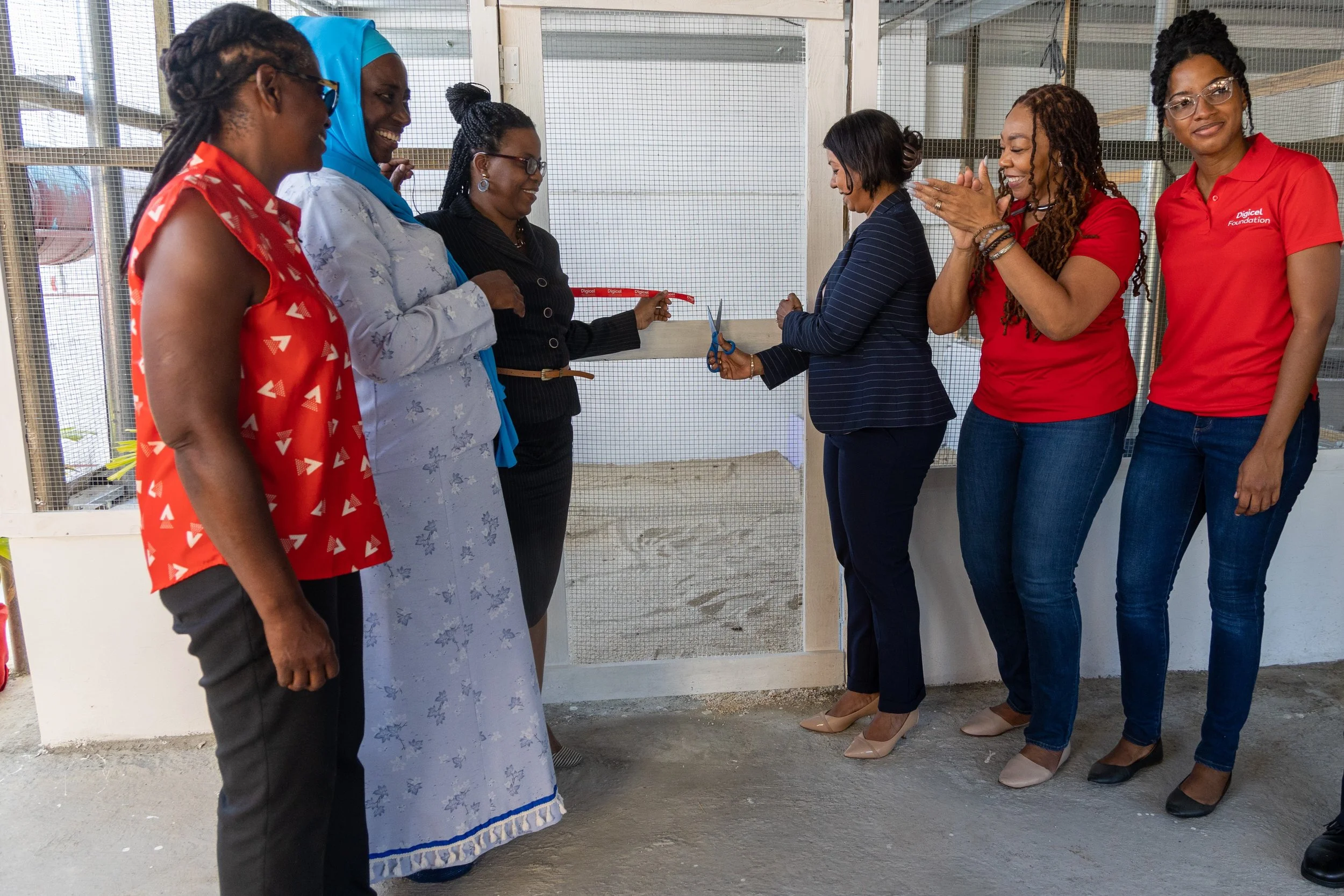 Digicel Foundation’s Chairperson Desha Clifford (centre right) cuts the ribbon on a chicken pen, launching the Tobago School for the Deaf, Speech and Language Impaired’s agro-science project to a round of applause from the Foundation’s CEO Penny Gomez. Also present, from left to right, are Olive James, Secretary, Tobago Agricultural Society; Cordella Pantin, Principal, Tobago School for the Deaf, Speech and Language Impaired; and Ann Second, Technical Advisor, Division of Education, Research and Technology; and Misha Jackman, Finance Accountant of Digicel Foundation.