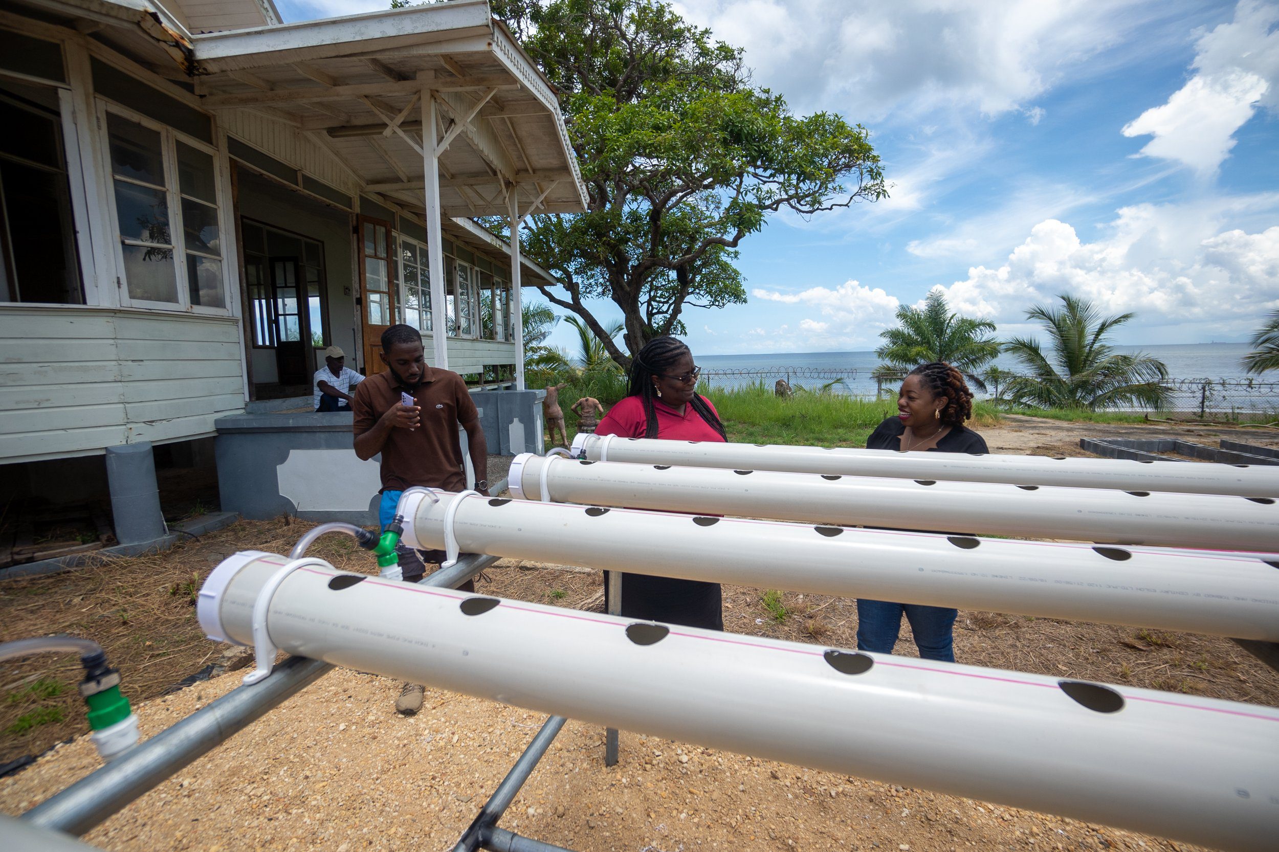 (L-R) Youth President/ Assistant Programme Manager Jillon Lewis, Leader of the La Brea Police Youth Club Woman Corporal Jasmine Vesprey-David and Digicel Foundation Operation Manager- Cindy ann Currency do a detailed walk through of the ongoing agricultural project at New Lands, La Brea