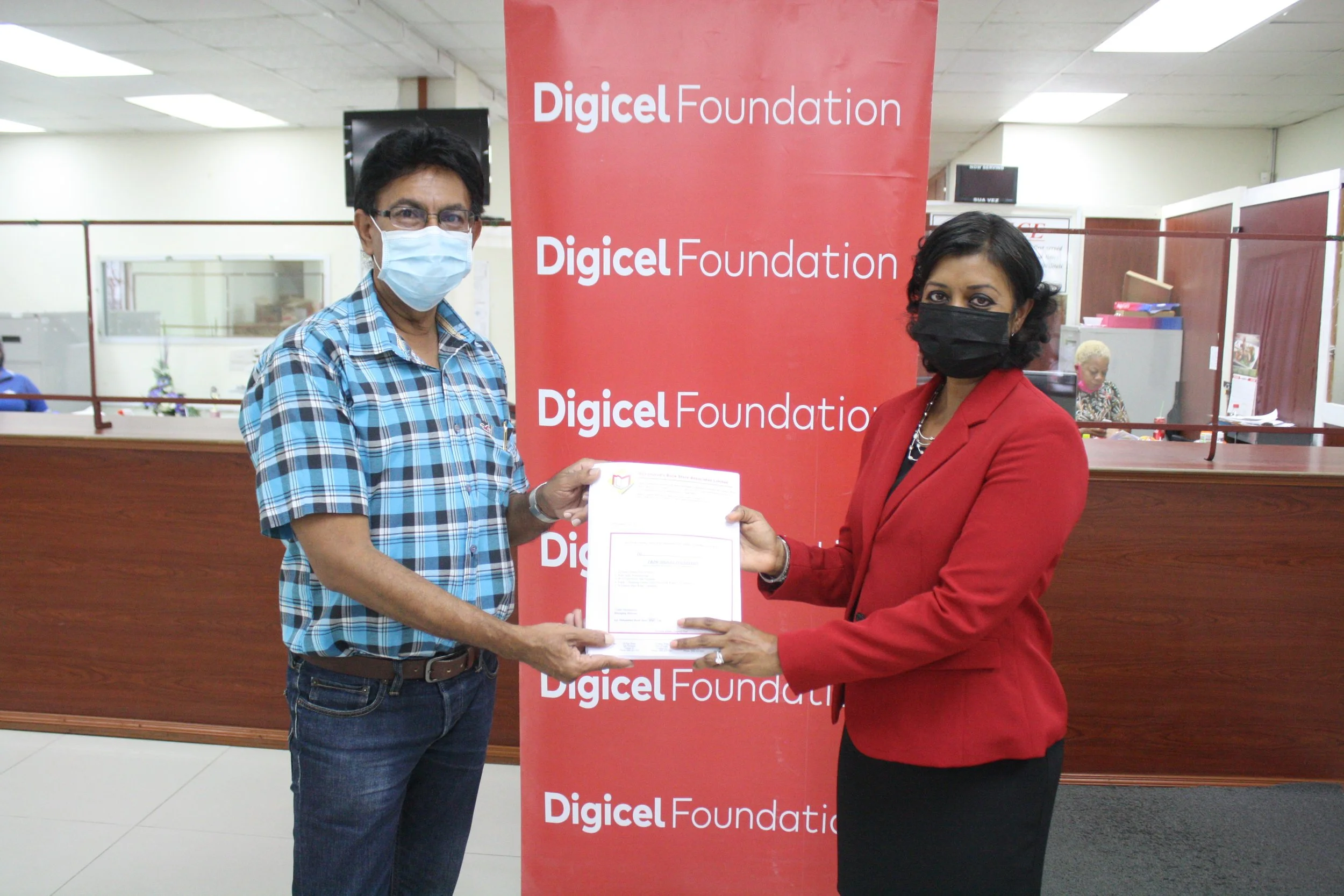 (L-R) Councillor Ryaad Hosein for Les Efforts East/Cipero receives vouchers from Chairperson of the Digicel Foundation, Mrs Desha Clifford