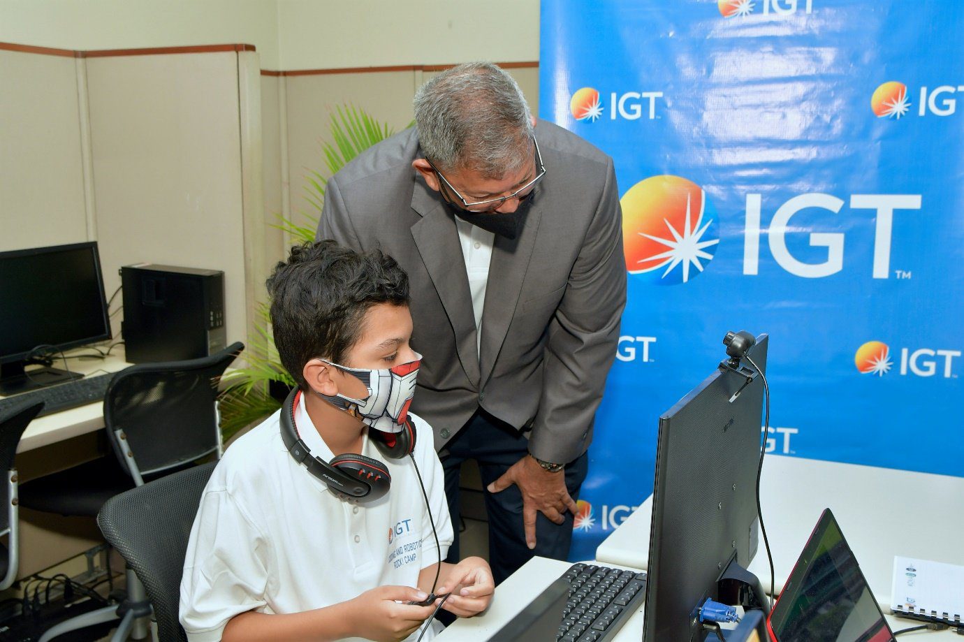 IGT Country Manager, Roger Bolai (right) guides a student through one of the IGT Coding and Robotics Rock! Camp classes during an executive team visit to The Cotton Tree Foundation on July 22nd, 2022.