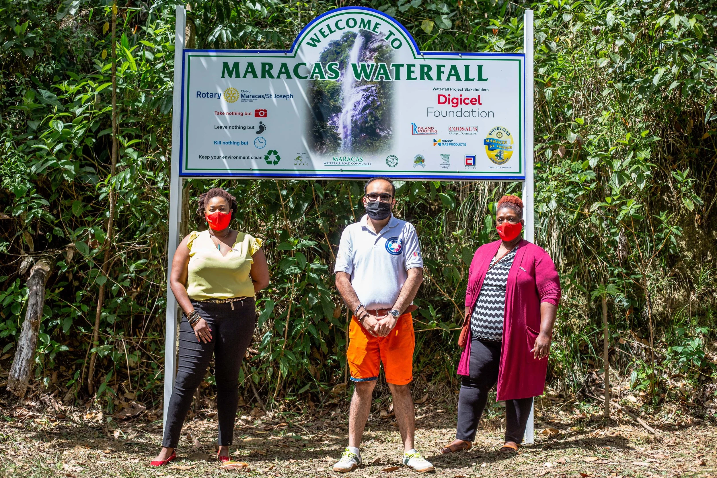 Digicel Foundation Operations Manager- Cindy Ann Currency, Rotary Member Christian Niranjan and Digicel Foundation Board Member, Laura Dowrich-Phillip stand in front of the newly erected sign welcoming visitors to the Maracas Waterfall location.
