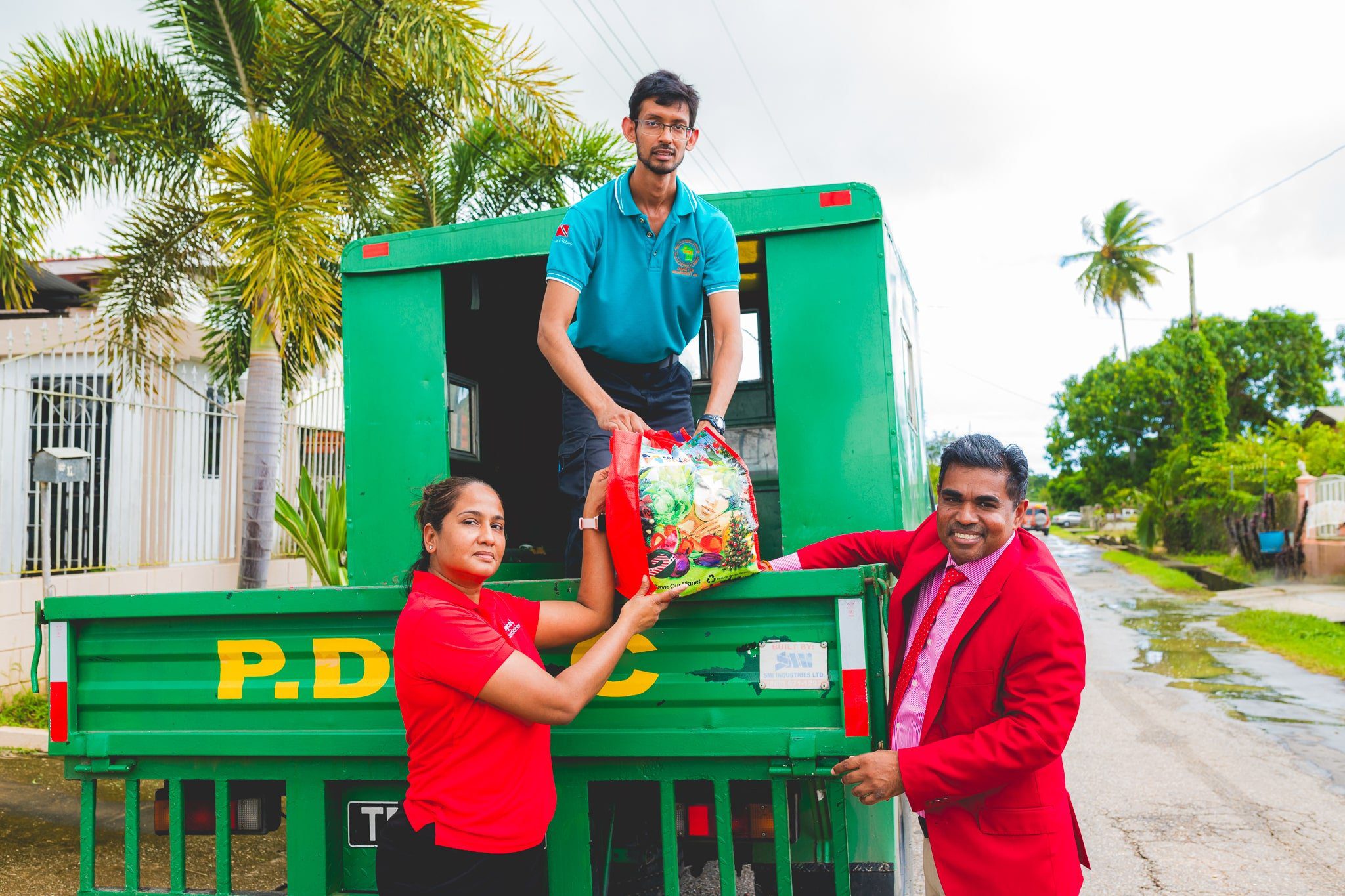 Diana Mathura-Hobson, Project Officer at Digicel Foundation, and Alderman Gowtam Maharaj, Chairman of the Penal Debe Corporation, assisted by a PDRC employee, offloaded hampers for families in flood-affected areas.