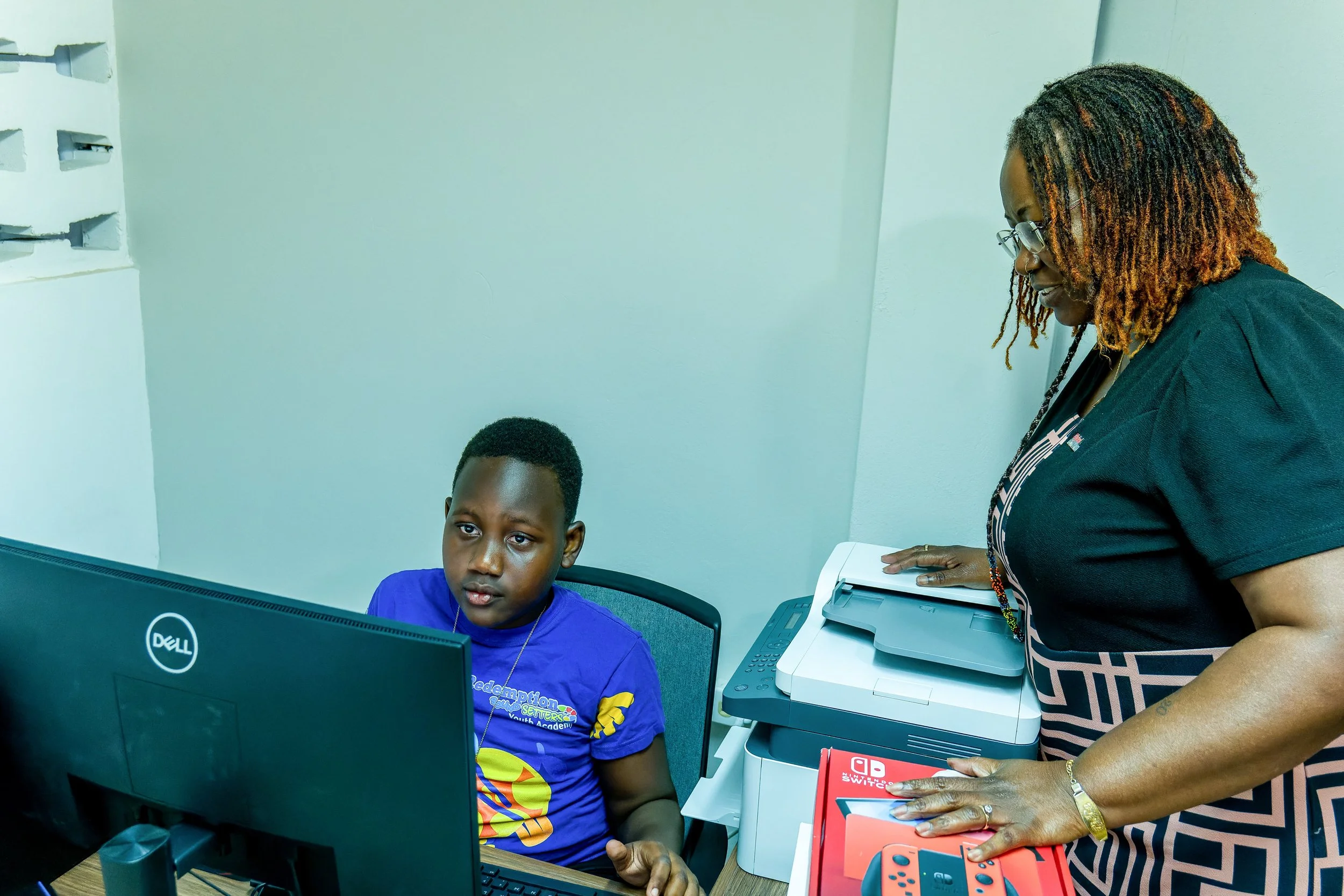 Digicel Foundation Director LaToya Gopaul assists a young band member using the new computers at Desperadoes Panyard on 25 March.
