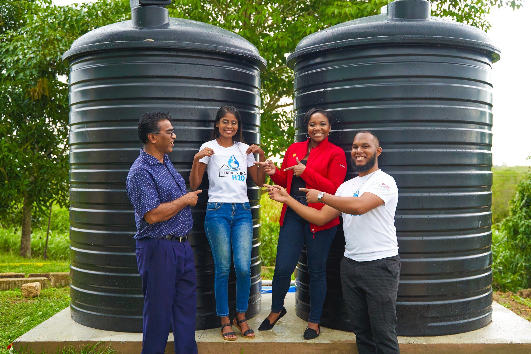 (L-R) Evangeline Pardasie, Founder of the EVA Foundation, proudly displays her “harvesting H2O” t-shirt at Picton Presbyterian Primary School, with the school’s teacher Mr. Mathura (on the left), Shell T&T’s Social Performance and Social Investment Advisor, Ryssa Brathwaite, and EVA Foundation Director Keston James.