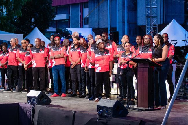 Members of PanTrinbago join Digicel Foundation CEO Penny Gomez (at the podium) on stage during the World Steelpan Day Celebrations on 11 August 2023, Woodford Square, to announce their partnership to commission eight Technology in Education (TIE) Centres at panyards.