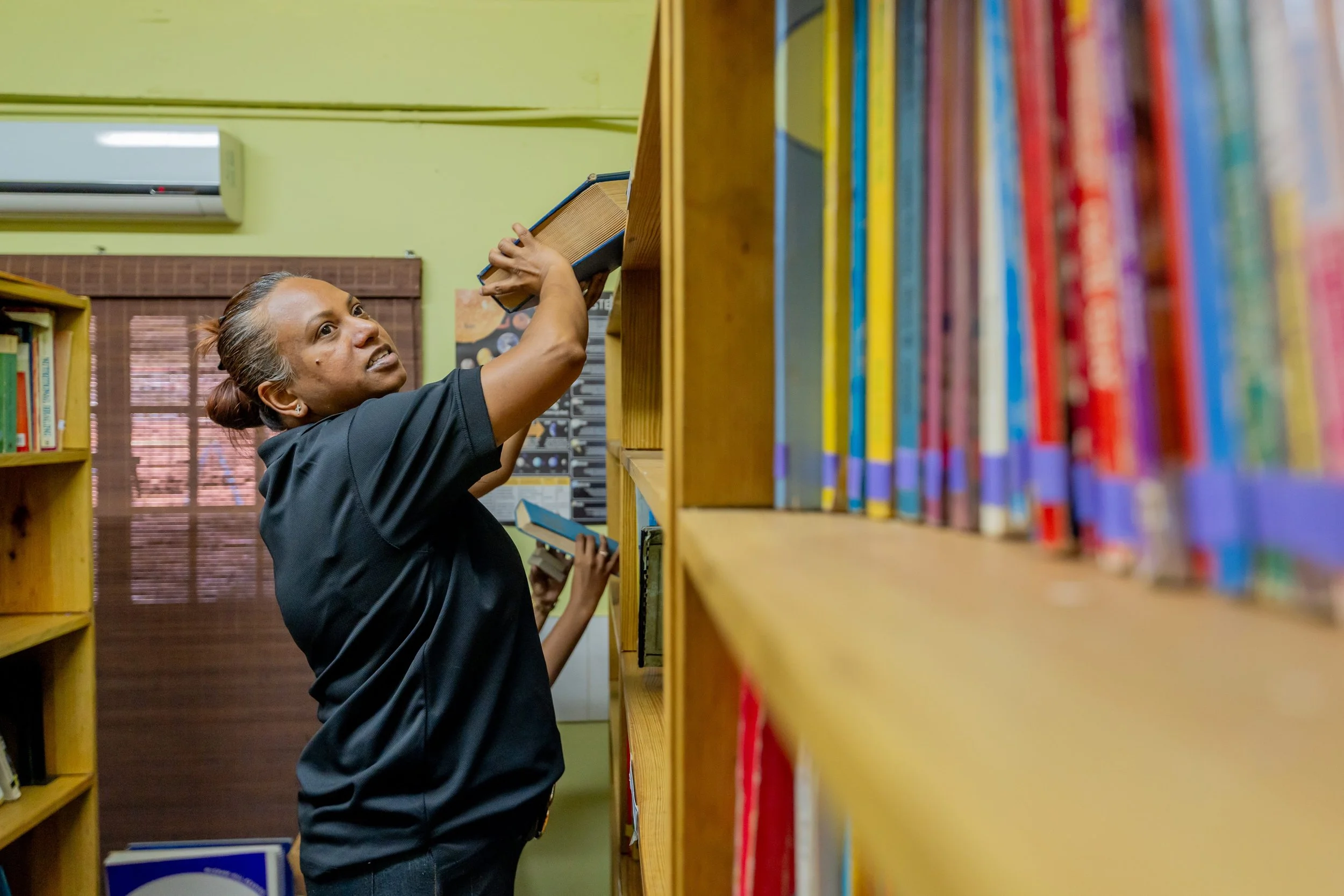 Devika Harricharan, IGT Relationship Strategy Officer and Global Giving Month Volunteer, carefully organizes, sorts and stacks Amica House’s library during the company’s Global Giving Month.