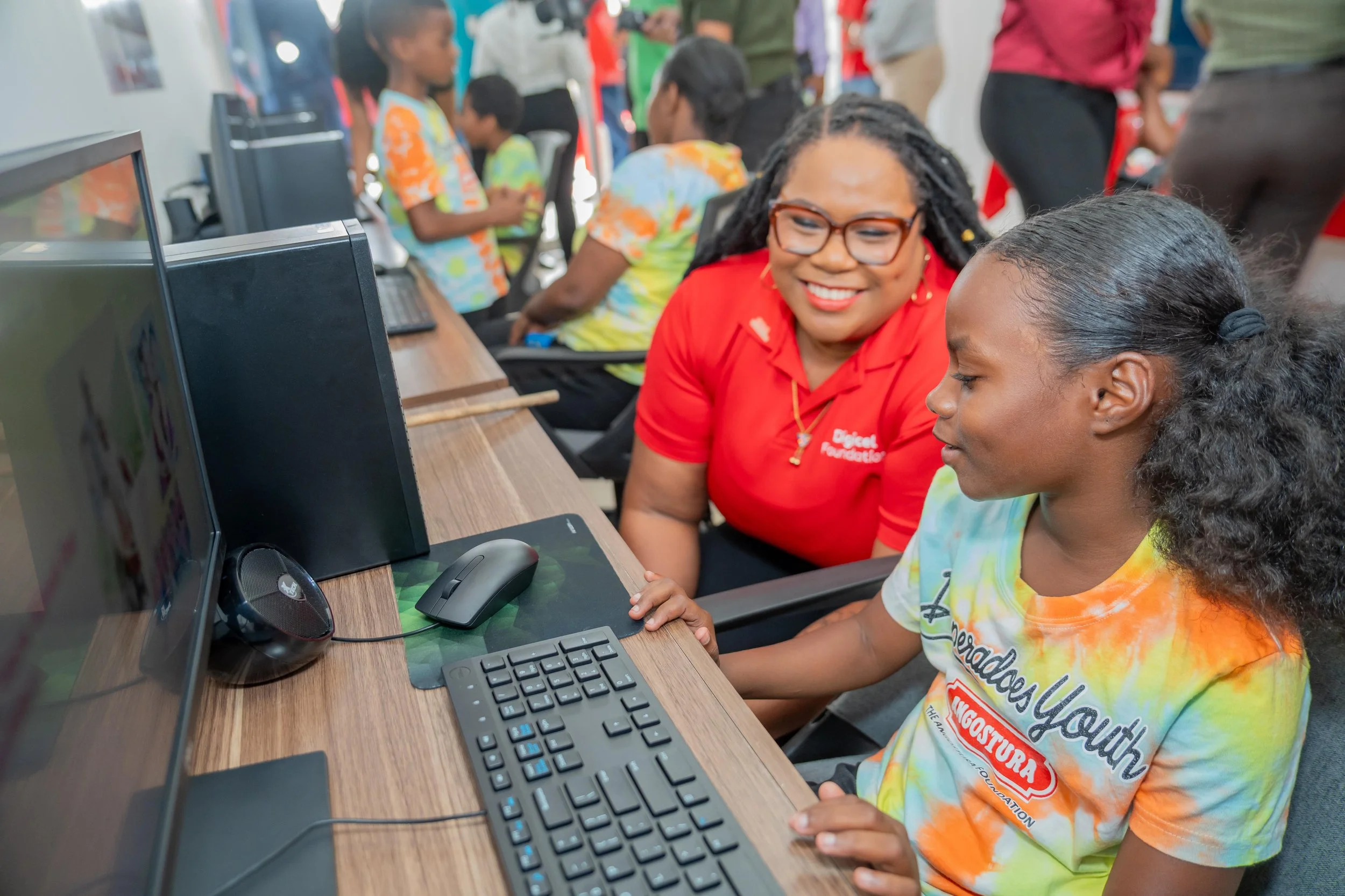 Digicel Foundation Director LaToya Gopaul assists a young band member using the new computers at Desperadoes Panyard on 25 March.