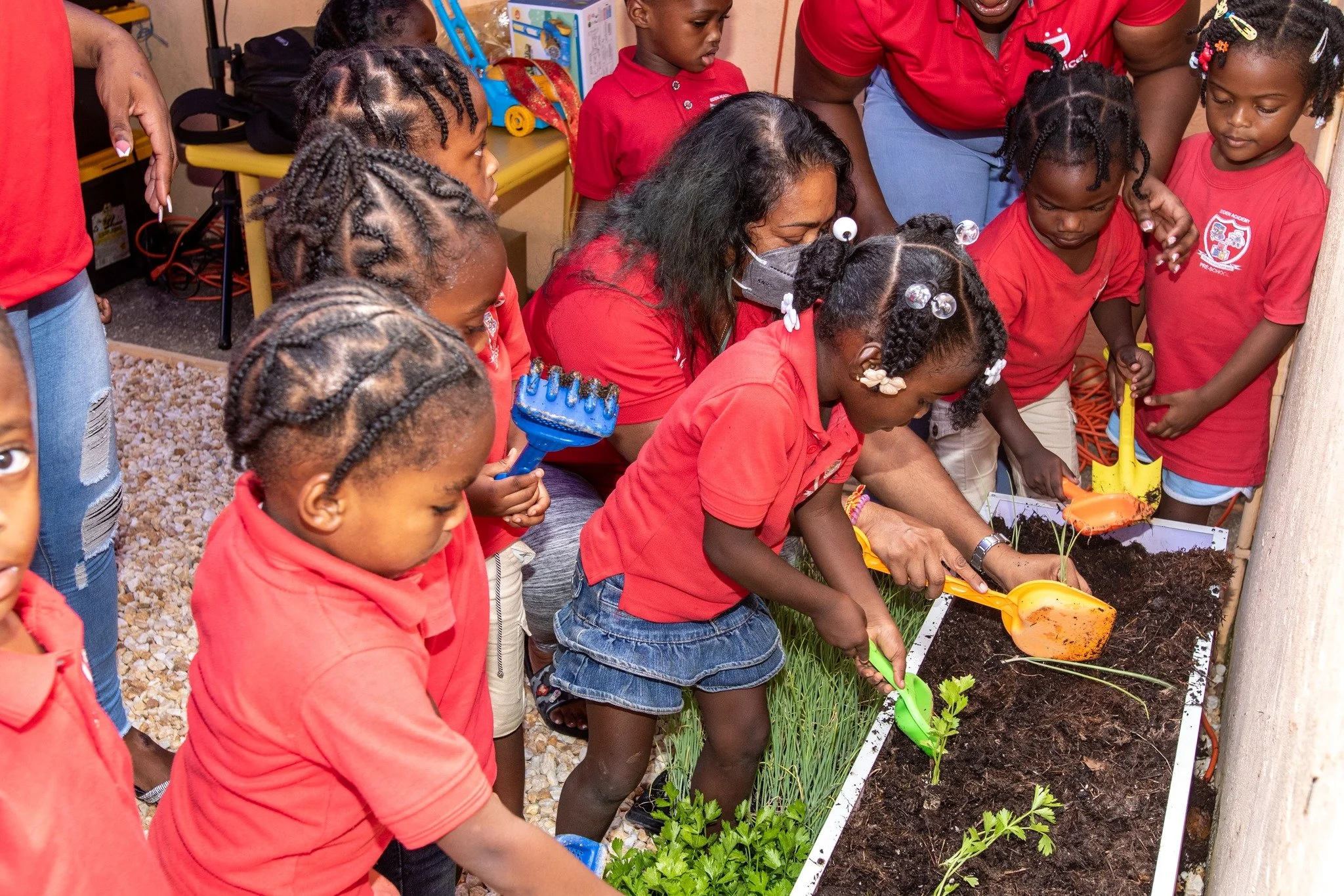 Digicel Foundation Board Director Pamela Sankar engages in a fun planting exercise with preschoolers of Eden Academy in their newly donated plant grow box.
