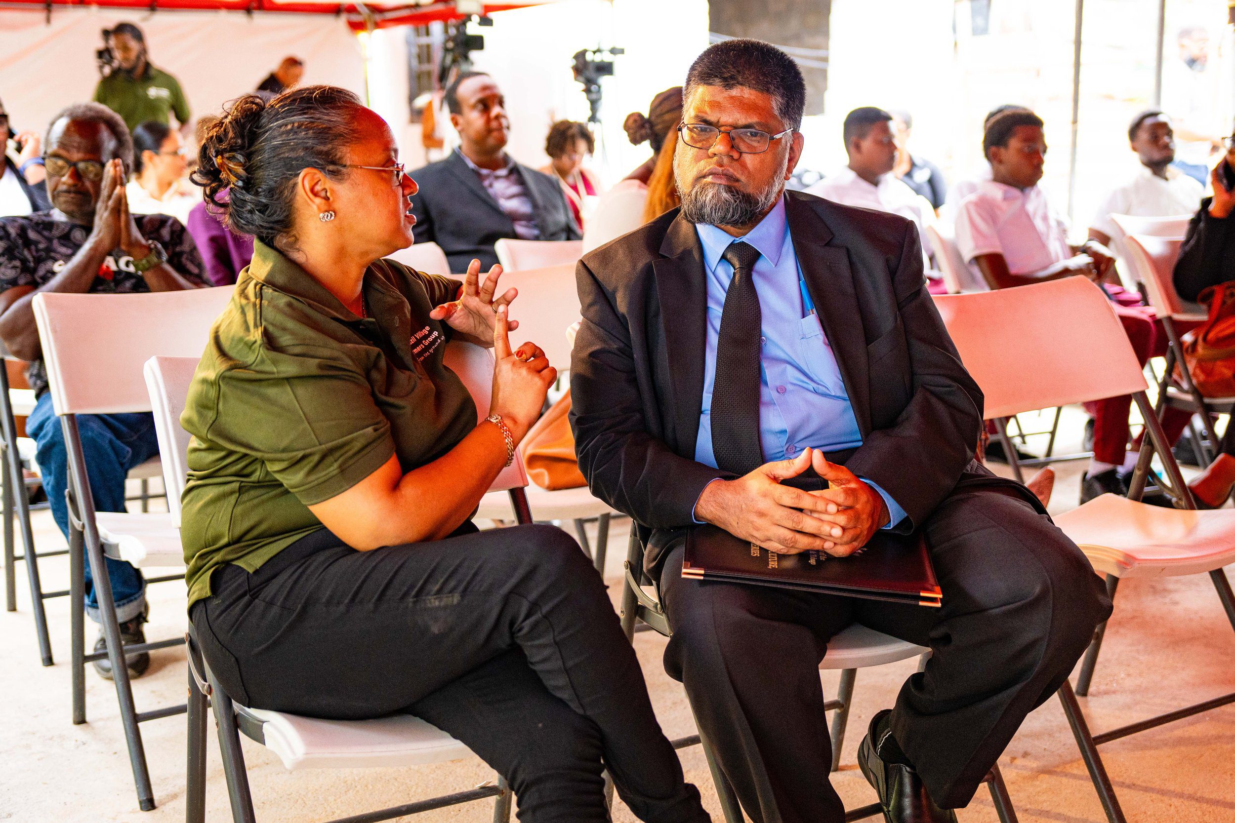Mr. Farook Hosein, Permanent Secretary in the Ministry of Agriculture, Land and Fisheries, listens intently to Maricia Patterson, Secretary of the Brazil Village Farmers Group, at the launch of the Brazil Village Farmers Group Agro-Processing and Packaging Facility, Brazil Lome Trace, on Wednesday 21 February 2024.