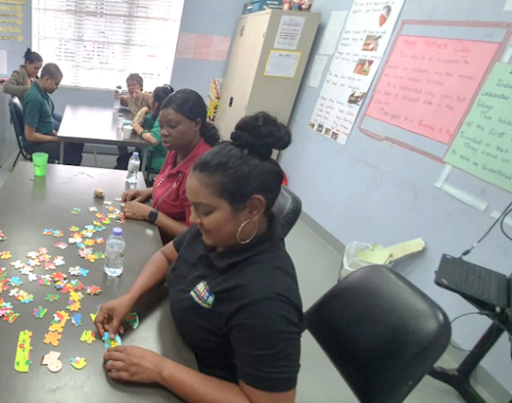 IGT volunteer Tanya Singh and Crystal Rodney share a moment as they build a puzzle with pre-vocational students of Immortelle Centre.