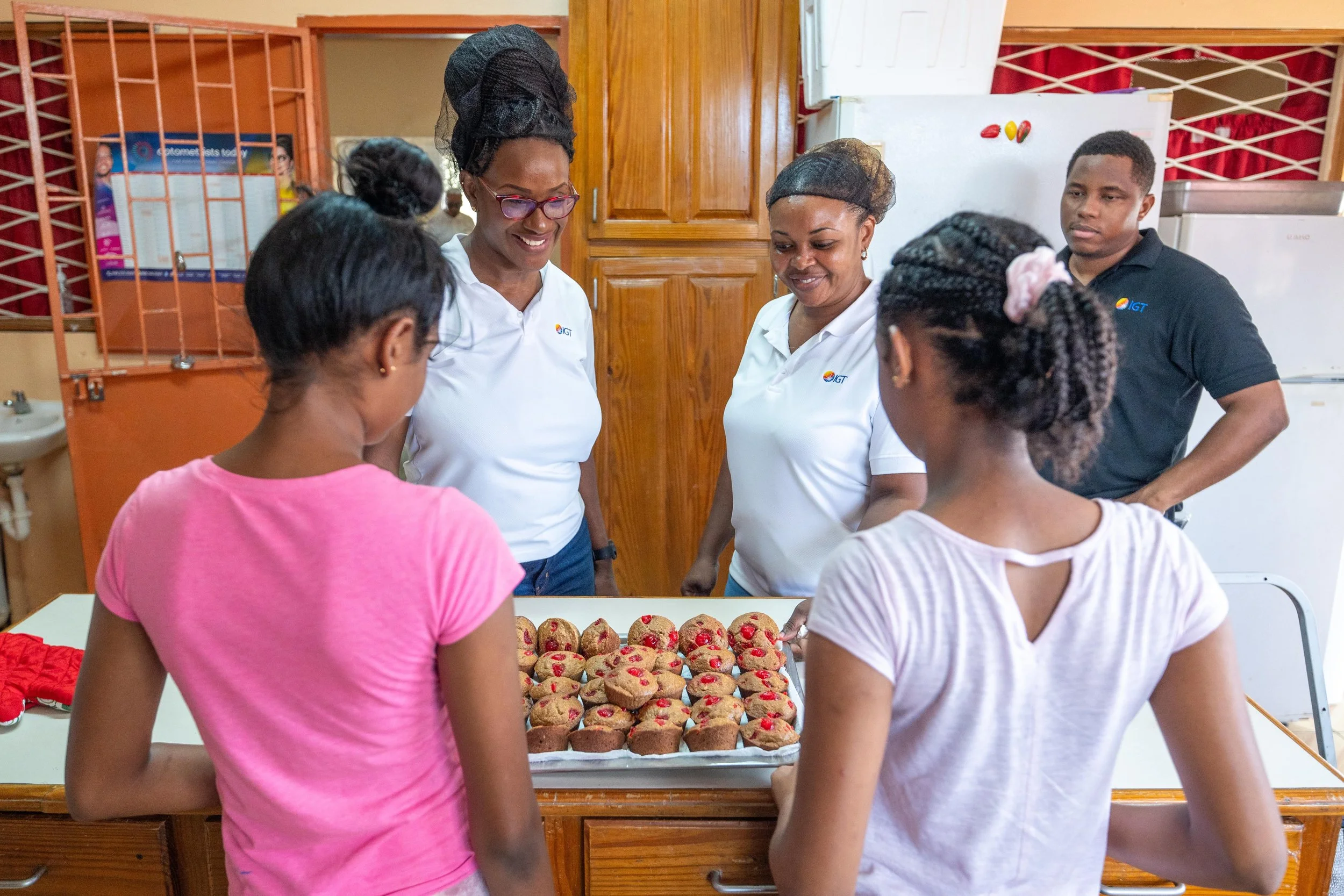 The day was a delicious success! Cherisse Charles-Bradshaw, IGT Chief Accountant, Rowen Marshall, IGT Call Center Associate, and Deshawn Bruce, IGT Repair Technician, admire the sweet outcome of their work in the kitchen at Amica House during IGT’s Global Giving Month.