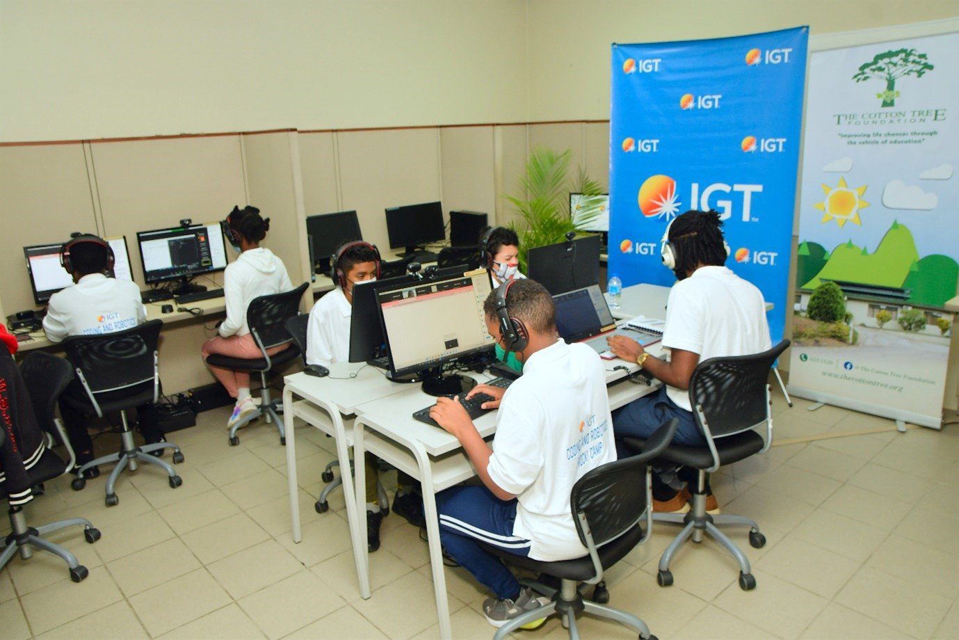 (L-R) Mr. Brendan Hames, IGT Caribbean Regional Director, Ms. Sita Persad - Executive Director at the Cotton Tree Foundation assists one of the students during a session of the second staging of IGT’s Coding and Robotics Rock! Camp.